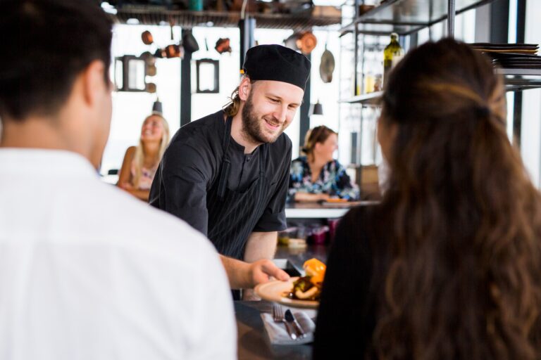 Happy chef serving dish to customers at Skybar restaurant
