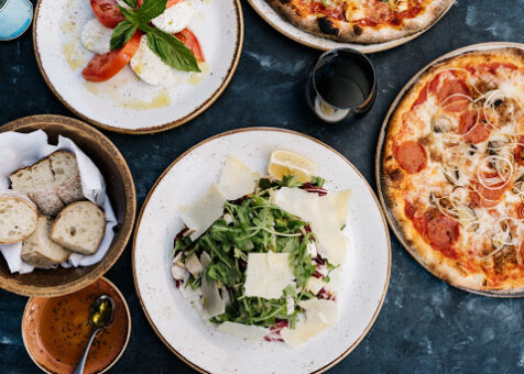 Arugula and Parmesan salad surrounded by other Italian foods.